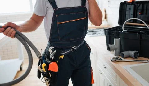 Cut view of man standing in kitchen and holding hose. He wear working uniform 库存照片