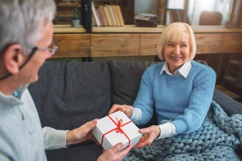 Cut view of nice and cute grandparents. He is giving a gift to h Stock Photos