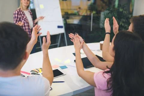 Cut view of people clapping in hands. They look at blonde woman standing near Stock Photos