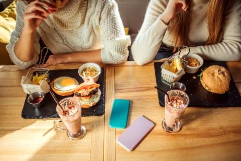 Cut view of table full of food and drink. There are young women sit at table Foto stock