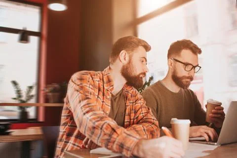 Cut view of two hipsters studying in cafe. One of them is working on computer Stock Photos
