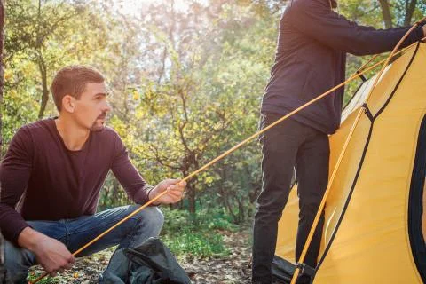 Cut view of two men working. First holds rope while another touches tent. They Stockfoto's