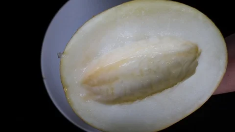 Cut the yellow melon on a white flat plate with a knife Stock Footage 96186902