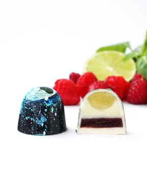 Cutaway chocolate candy. Raspberry, lime and basil on a white background Foto stock