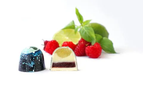 Cutaway chocolate candy. Raspberry, lime and basil on a white background Stock Photos