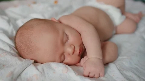 Cute 2 weeks old newborn baby is sleeping on the bed. Close up shot. Stock Footage 111772016