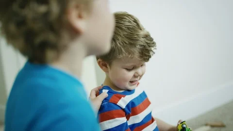 Cute 2 year old boy laughs dramatically at big brother's joke over the shoulder Stock Footage 127549512