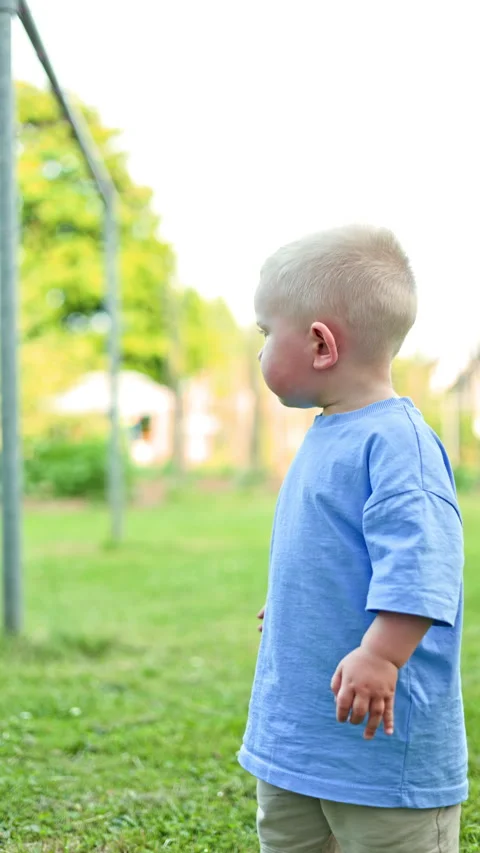 Cute 2 year old boy in a blue t-shirt and blue shorts on a walk in the park. The Stock Footage 319932378
