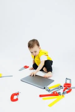 A cute 2-year-old boy is sitting at a digital laptop on a white background... 写真素材
