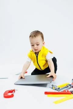 A cute 2-year-old boy is sitting at a digital laptop on a white background... Stockfoto's
