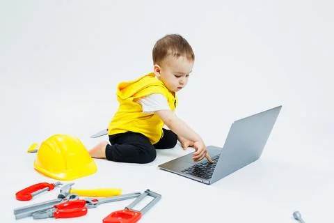 A cute 2-year-old boy is sitting at a digital laptop on a white background. C Stockfoto's