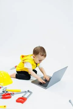 A cute 2-year-old boy is sitting at a digital laptop on a white background... Foto stock