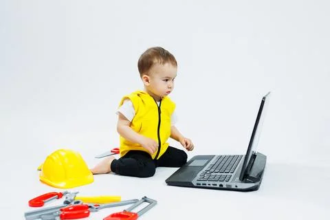 A cute 2-year-old boy is sitting at a digital laptop on a white background. C 写真素材