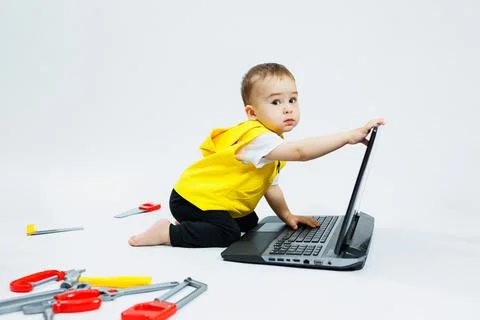 A cute 2-year-old boy is sitting at a digital laptop on a white background. C 写真素材