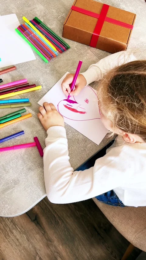Cute 4-year-old blonde girl concentrates while drawing sitting at table. Child Stock Footage 308386680