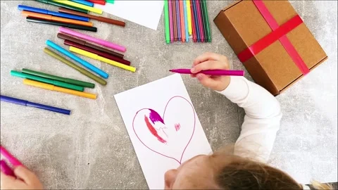 Cute 4-year-old blonde girl concentrates while drawing sitting at table. Child Stock Footage 308719679
