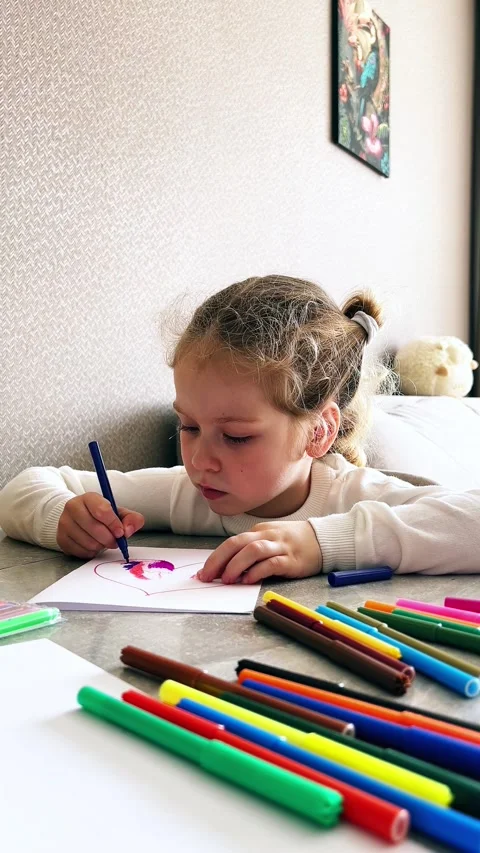 Cute 4-year-old blonde girl concentrates while drawing sitting at table. Child Stock Footage 310605828