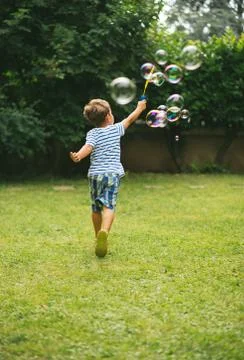 Cute 5 year old child running making soap bubbles Stock Photos