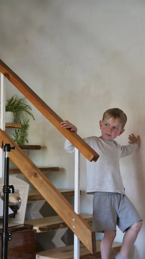 A cute 6-year-old boy is walking down the stairs in a country house Stock Footage 334582974