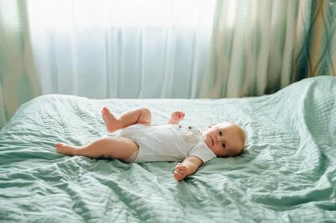 Cute 7-8 Month Old Healthy Baby on a Bed at Home Stock Photos