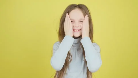 Cute 8-9 year old girl straightens her long hair, preens at the camera on a yell Stock Footage 277498641