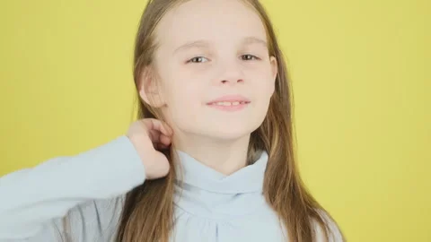 Cute 8-9 year old girl straightens her long hair, preens at the camera on a yell Stock Footage 278050323