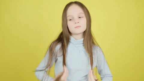 Cute 8-9 year old girl straightens her long hair, preens at the camera on a yell Stock Footage 279653687