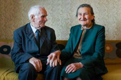 Cute 80 plus year old married couple posing for a portrait in their house. Stock Photos