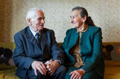 Cute 80 plus year old married couple posing for a portrait in their house. Stock Photos