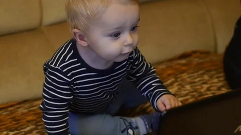 Cute 9-10 months old boy watching animated video on pc Stock Footage 82571356
