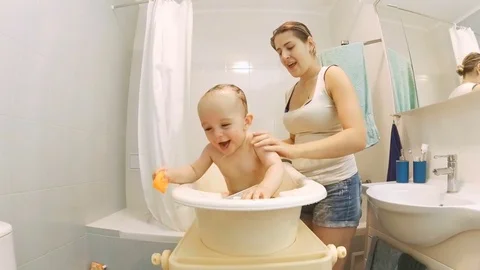 Cute active baby boy bathing with young smiling mother Video stock 71985628