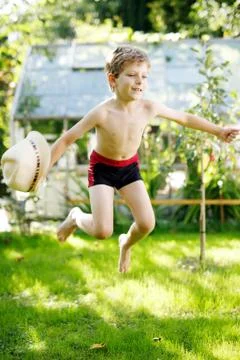Cute active kid boy jumping in the garden on warm sunny summer day. Happy kid Stock Photos