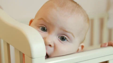 Cute, adorable baby, looking at the camera and nibbling a bed Stock Footage 125941296