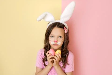 A cute, adorable, scared girl in a rabbit costume with ears and a painted fac Stock Photos