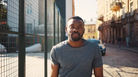 Cute African guy in gray T-shirt looking attentively at camera, holding Stock Footage 92054547
