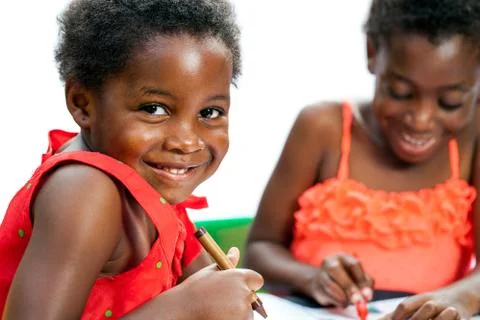 Cute african kid holding crayon with friend in background. Stock Photos