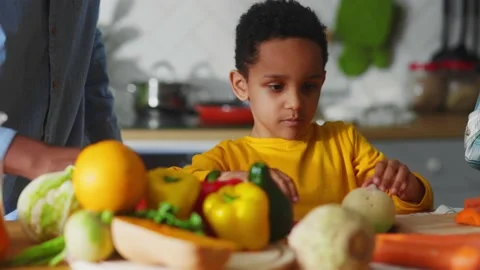 Cute african young kid boy helping his father cooking healthy lunch with fresh Stock Footage 147270789