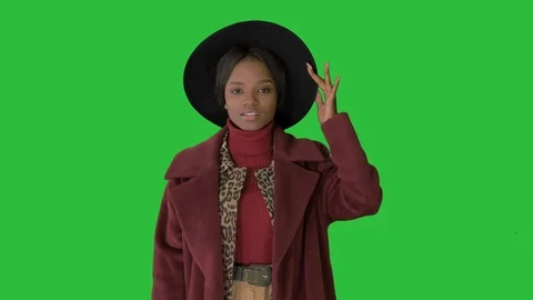 Cute afro model in coat touching hat walking on a Green Screen, Chroma Key. Stock Footage 125456865