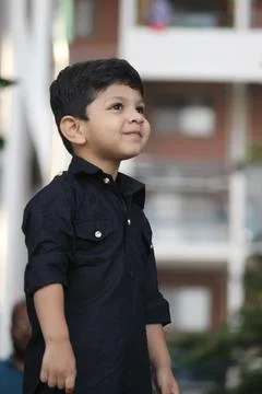 Cute and curious boy standing and looking at someone, He is wearing black pathan Stock Photos