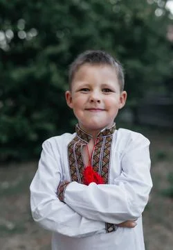 A cute and cute Ukrainian boy is standing on the street in an embroidered s.. Stock Photos