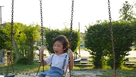 Cute Asian child having fun on swing in the park slow motion Stock Footage 91340499