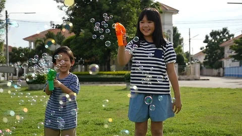 Cute Asian children Shooting Bubbles from Bubble Gun in the park slow motion Stock Footage 86041353