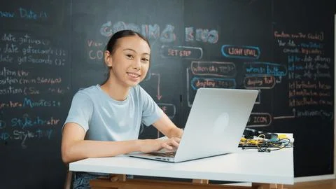 Cute asian girl programing system by using laptop at blackboard. Edification. 库存照片