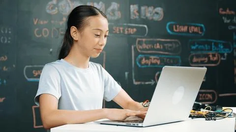 Cute asian girl programing system by using laptop at blackboard. Edification. 库存照片