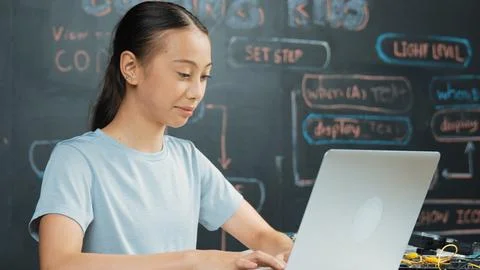 Cute asian girl programing system by using laptop at blackboard. Edification. 库存照片