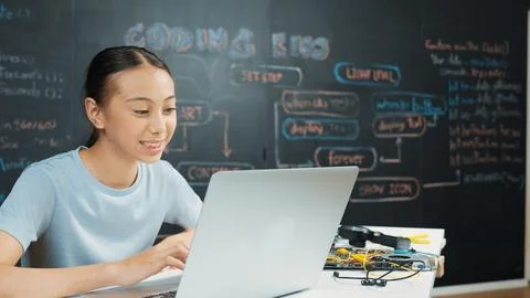 Cute asian girl programing system by using laptop at blackboard. Edification. 库存照片