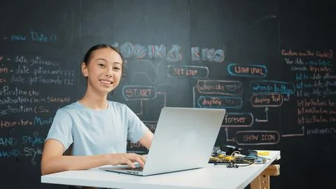 Cute asian girl programing system by using laptop at blackboard. Edification. 库存照片