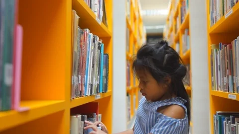Cute Asian little Girl Reading Books in School Class Library, Stock Footage