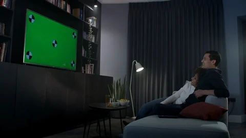 Cute, attractive couple snuggle on the sofa in front of the tv Stock Footage 100201642
