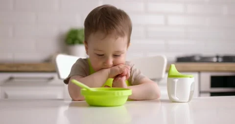 Cute baby boy does not want to eat, waves his head. Little child sitting on Stock Footage 154872495
